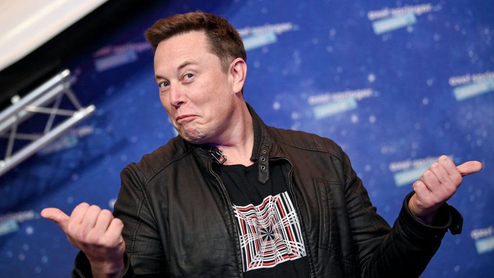 white man(elon musk) with hands apart and thumbs out